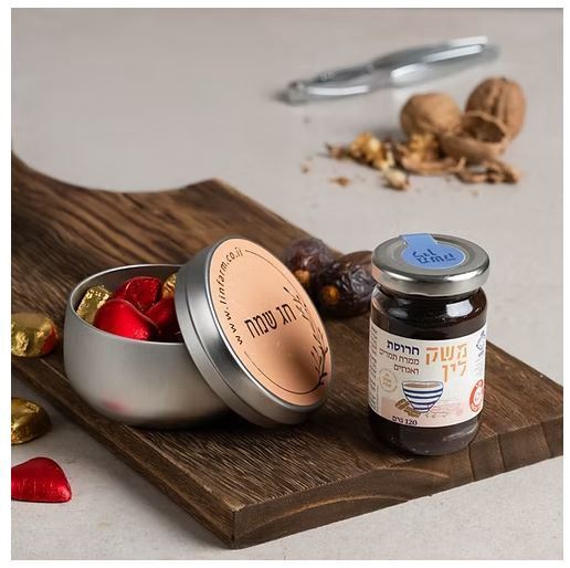 מארז חג שמח פסח -  
המארז כולל: 
חרוסת תמרים ואגוזים, 120 גרם.
קופסת פח מעוצבת עם לבבות שוקולד חלב ממולא קרם אגוזי לוז, 150 גרם.